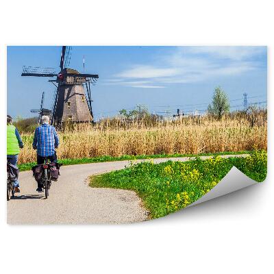 Papier peint Cyclistes masculins sur un chemin surplombant un moulin à vent