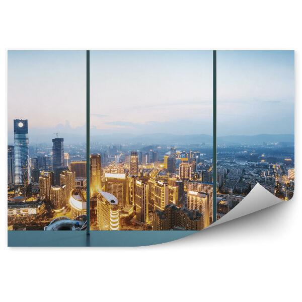 Papier peint Vue de la ville illuminée au crépuscule par la fenêtre